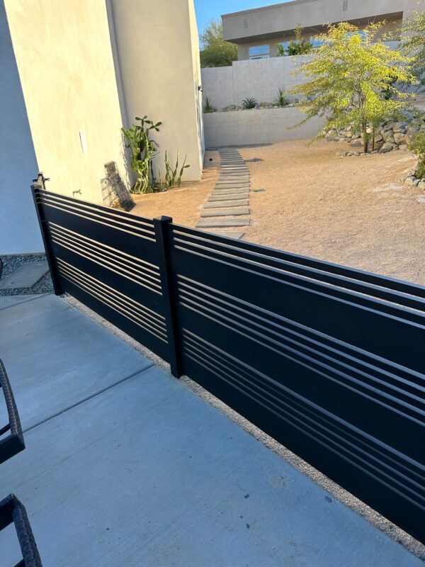 Matte black aluminum gate with horizontal slats, blending into a desert landscape.