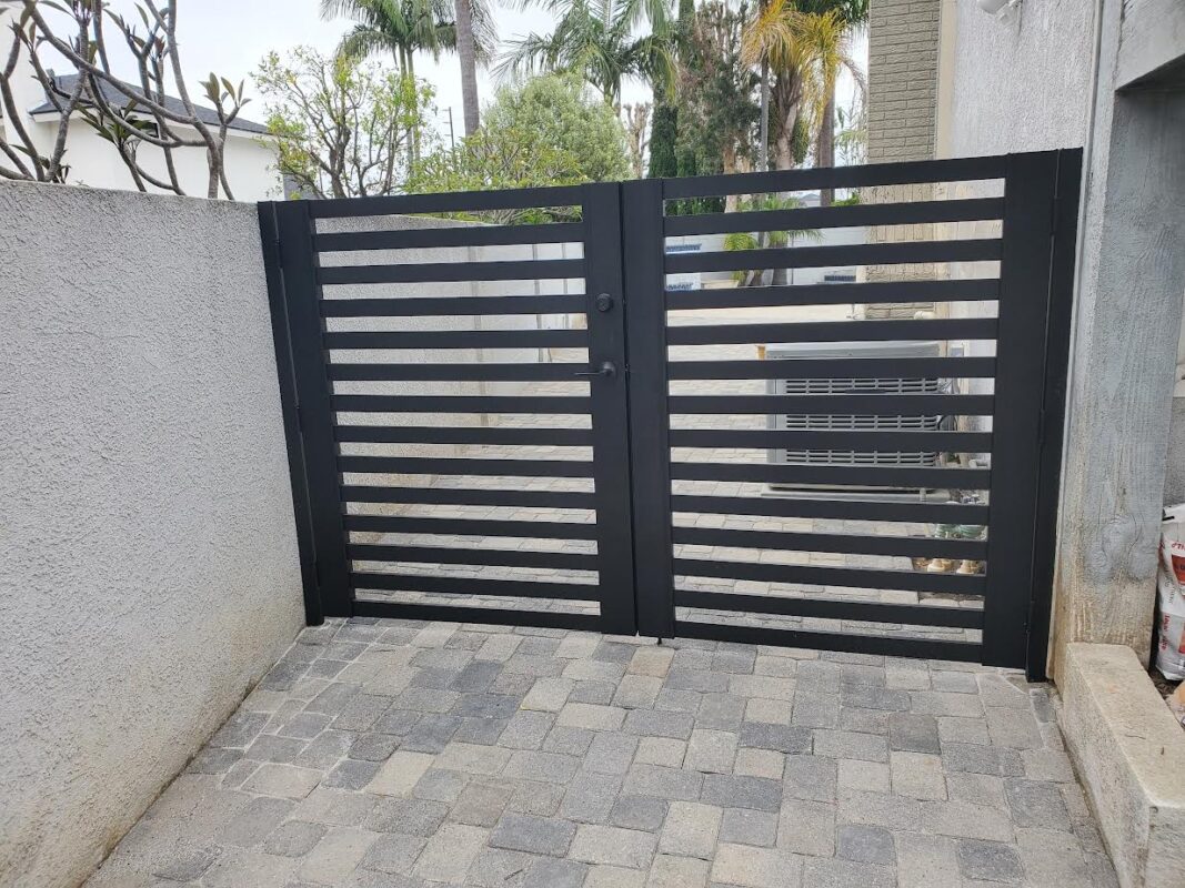 Black aluminum double swing gate in a modern residential fence installation.