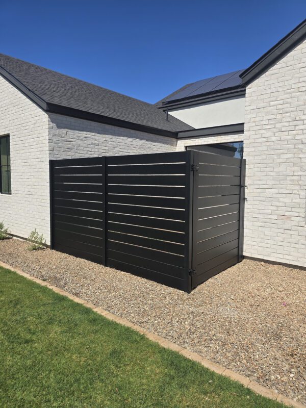 Modern aluminum privacy gate in satin black, sleek design with durable landscaping.
