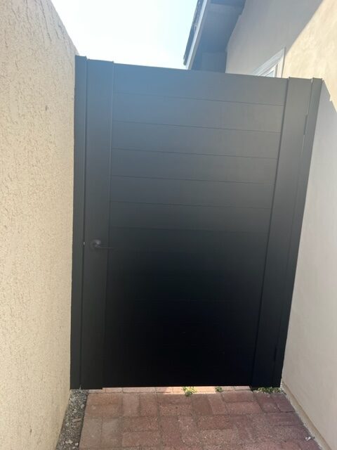 Matte black aluminum gate installed between two beige walls.