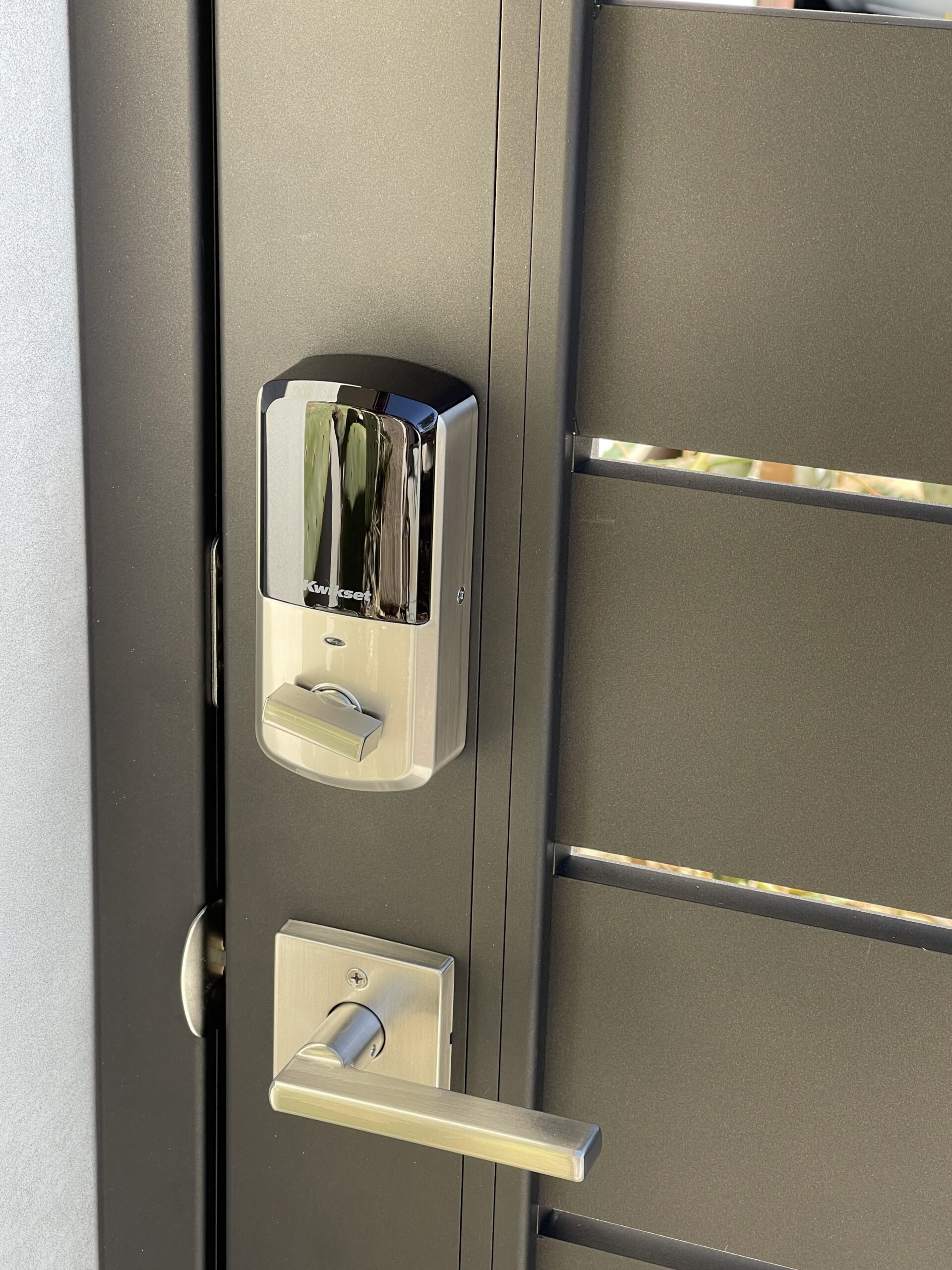 Close-up of a modern bronze aluminum gate lock mechanism.