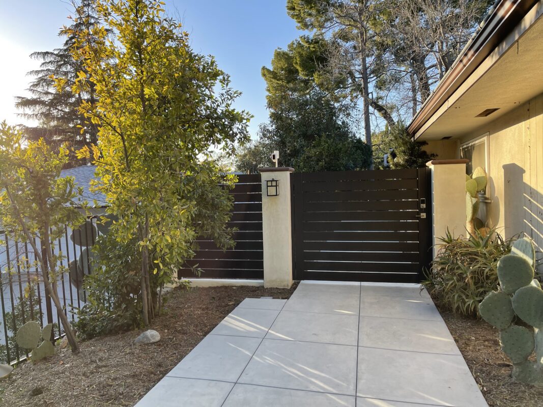 Modern bronze aluminum side yard gate installation with vibrant greenery.