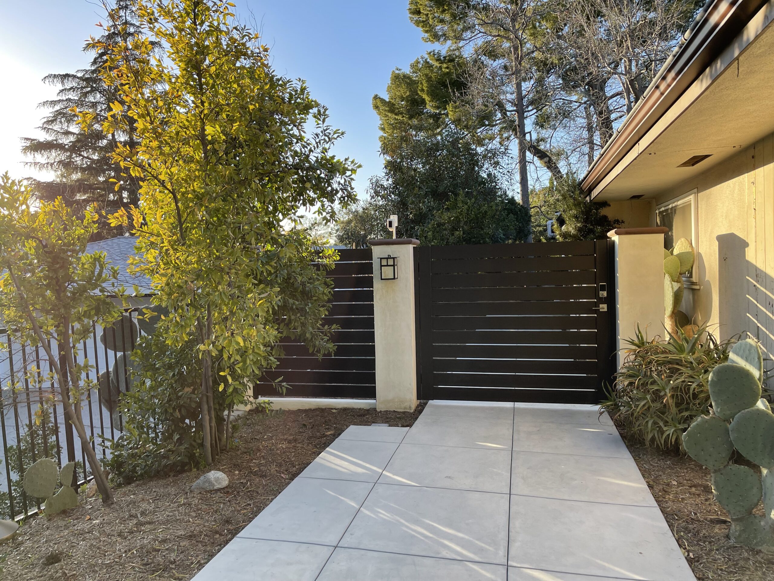 Modern bronze aluminum side yard gate installation with vibrant greenery.
