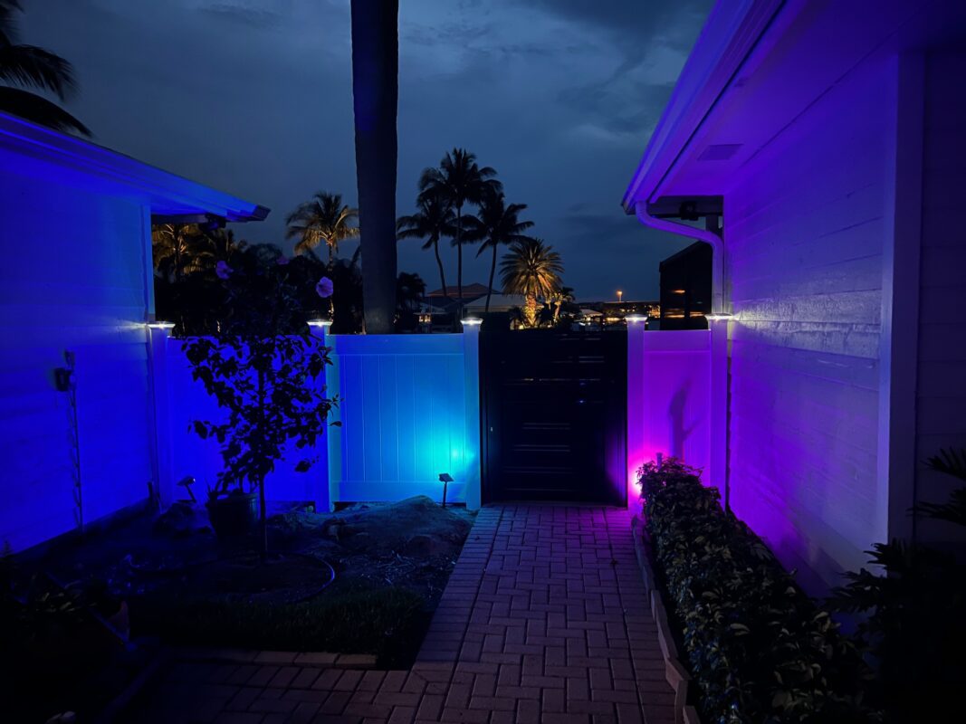 Modern aluminum pedestrian gate at night, illuminated with colorful lights in Vero Beach.