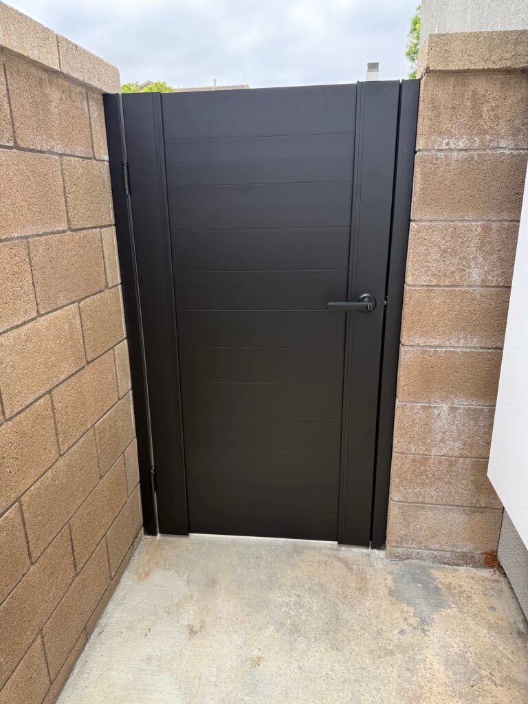 Matte black aluminum gate installed between stone walls, showcasing a modern design.