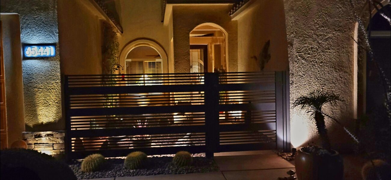 Modern aluminum fence and gate installation at night, showcasing horizontal slats.