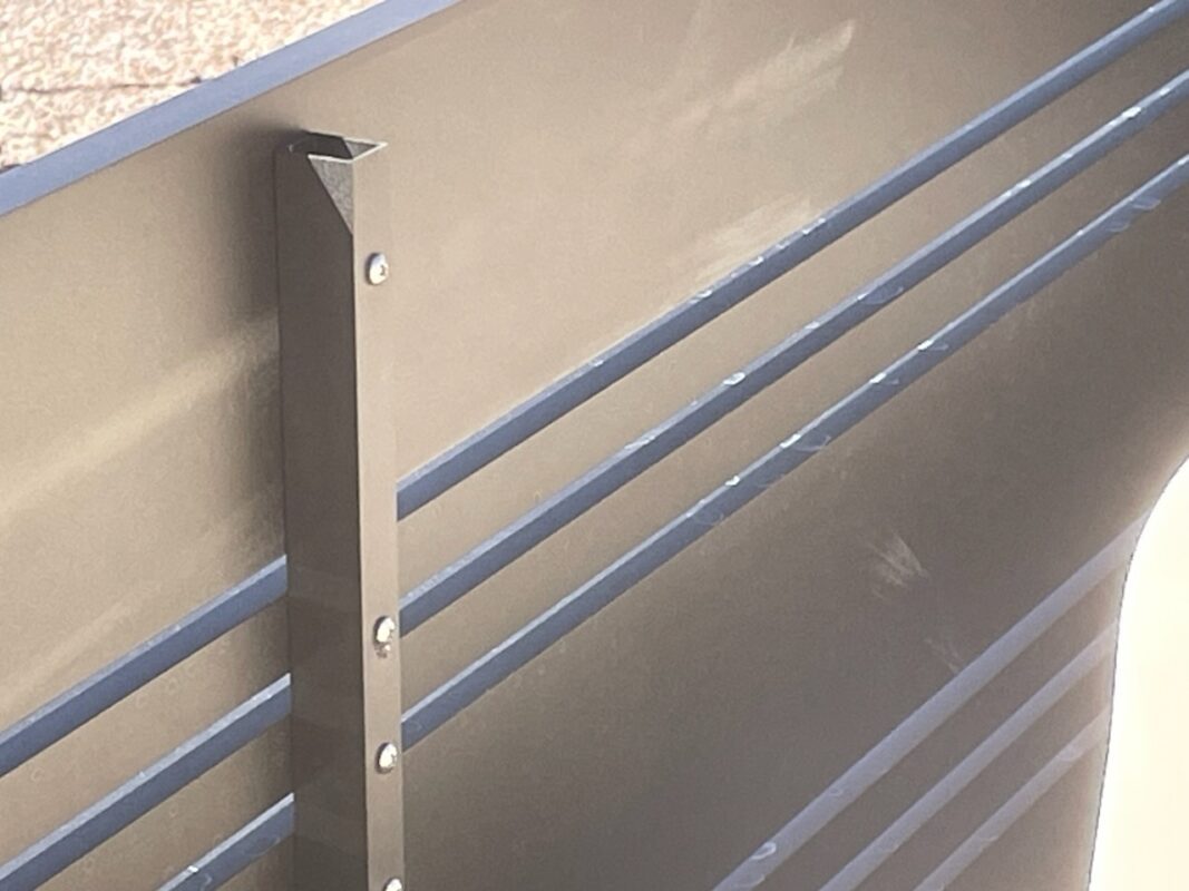 Close-up of a modern aluminum fence panel installation with bronze finish.