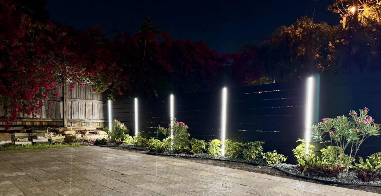 Modern aluminum fence installation with built-in lights, surrounded by vibrant flowers.