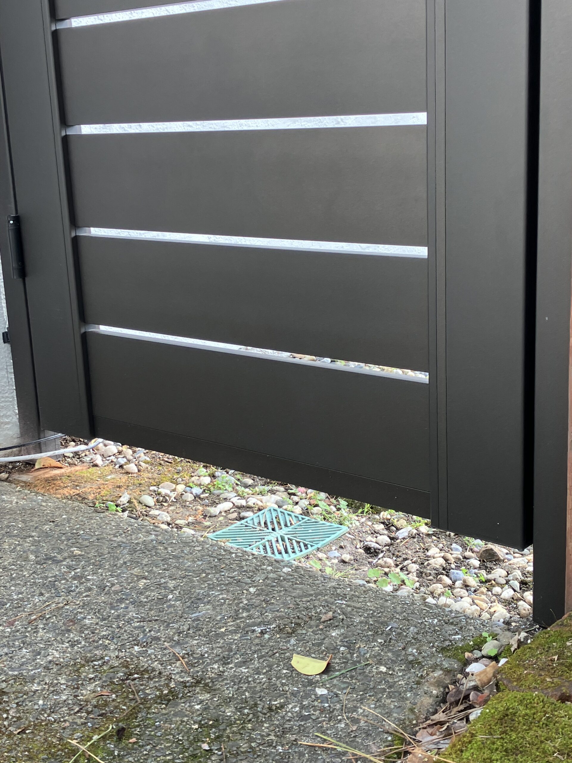 Close-up of a modern bronze aluminum pedestrian gate with horizontal slats.
