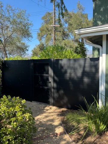 Matte black aluminum gate and fence in a residential setting with landscaped yard.
