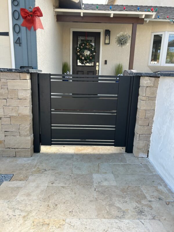 Modern black aluminum gate with horizontal slats, leading to a home's entrance.