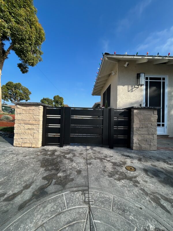 Modern aluminum gate with stone pillars at a home entrance in Ventura, CA.