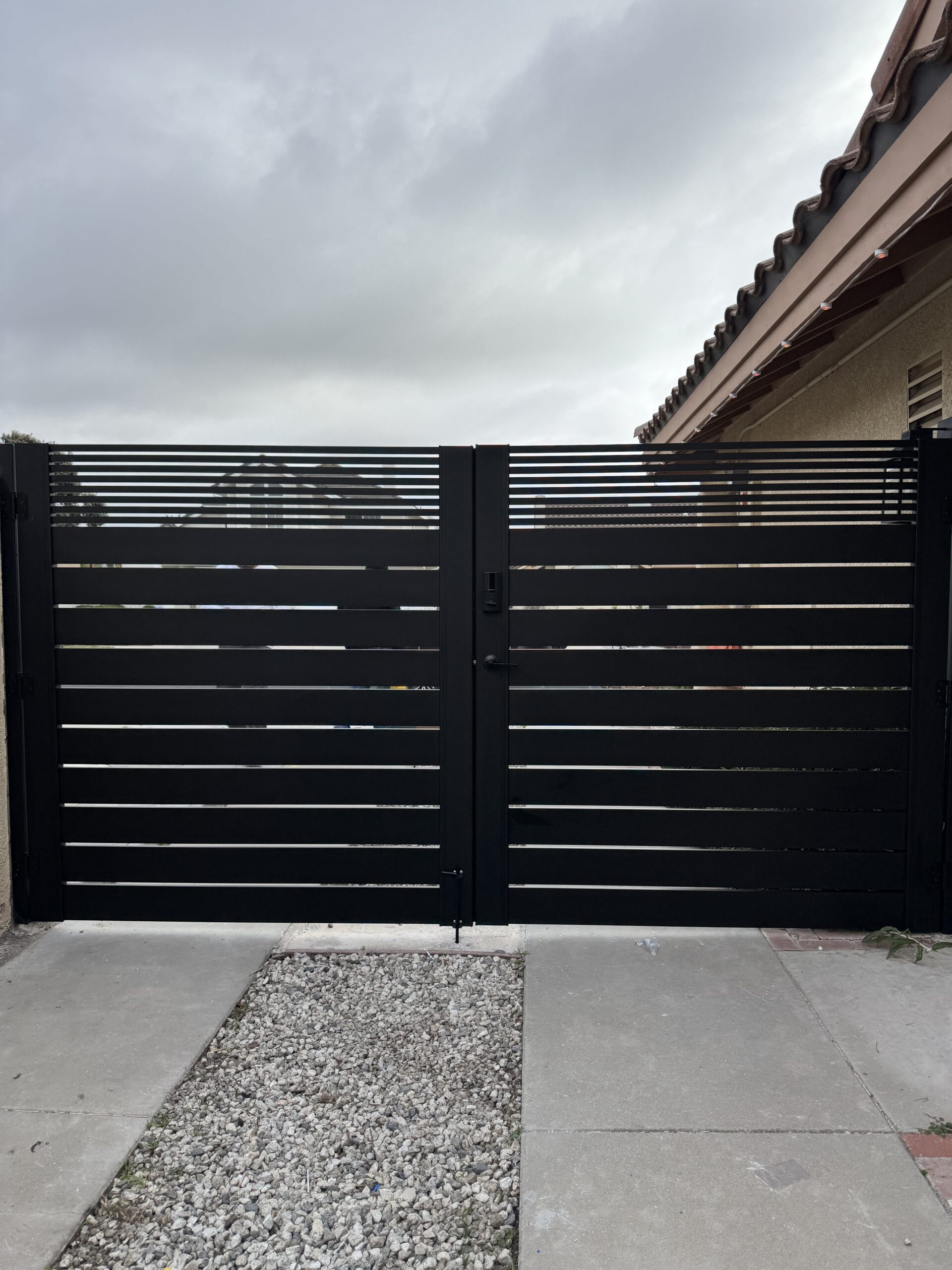 Modern matte black double swing gate with horizontal slats and sleek design.