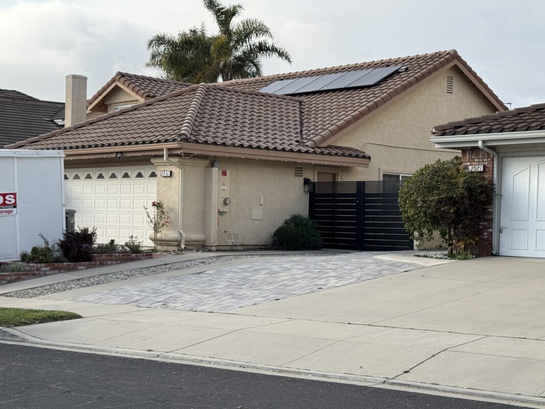 Modern double swing gate in matte black aluminum with horizontal slats in a residential driveway.