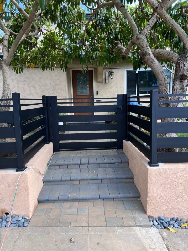 Matte black aluminum gate with semi-privacy slats and paver steps in San Diego.
