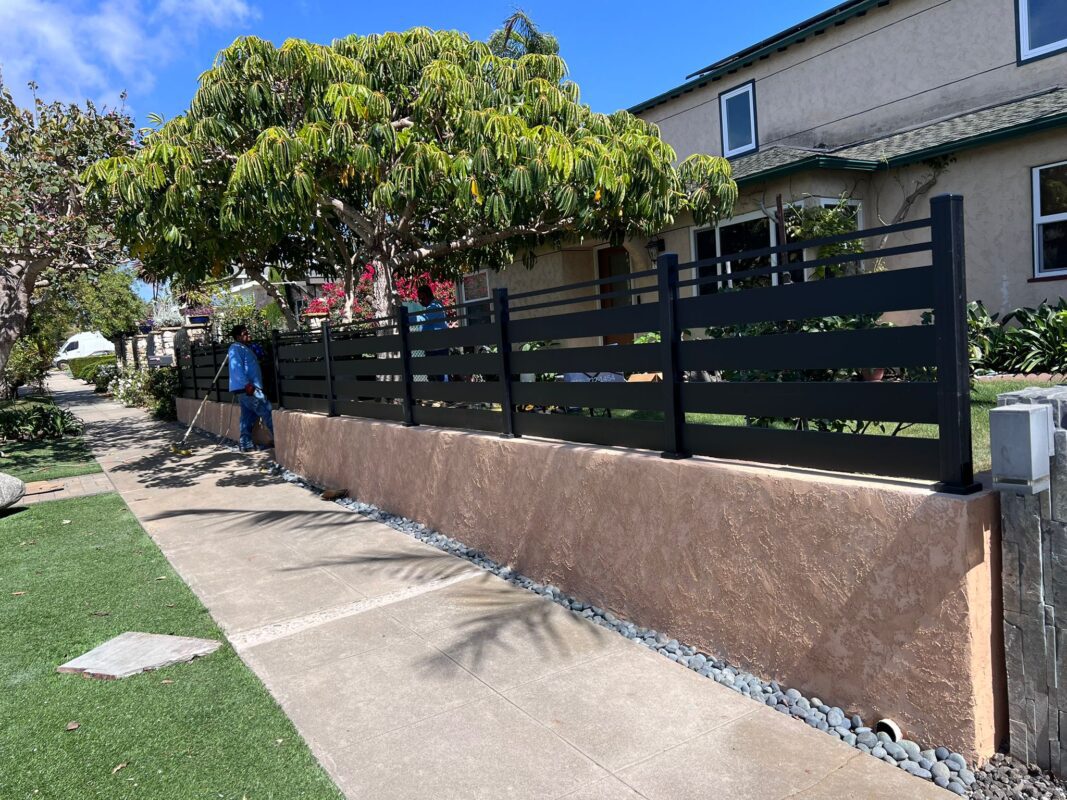 Matte black aluminum fence installation with semi-privacy slats in a residential area.