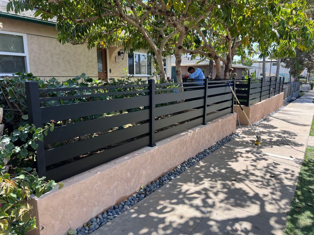 Matte black aluminum fence installation with semi-privacy slats in a residential area.