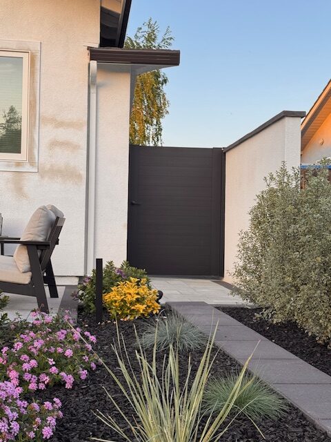 Matte black aluminum gate in landscaped yard, enhancing privacy and style.