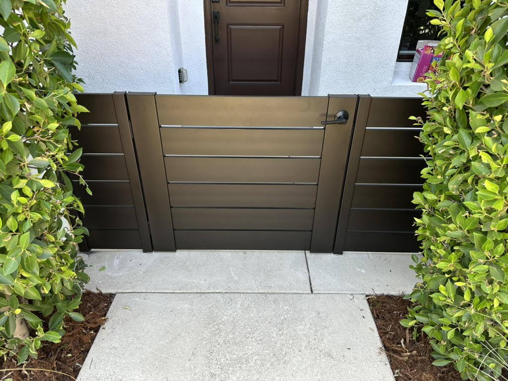 Modern bronze aluminum gate installed in a landscaped area, enhancing outdoor safety.