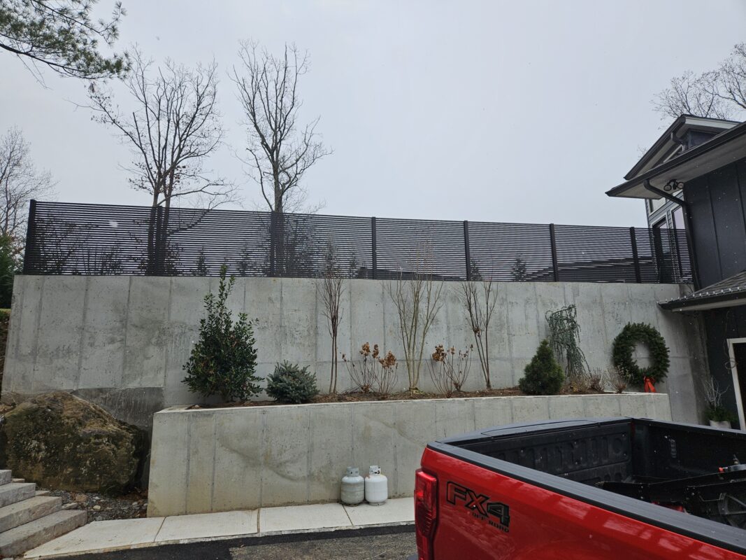 Black aluminum wall topper above a concrete wall
