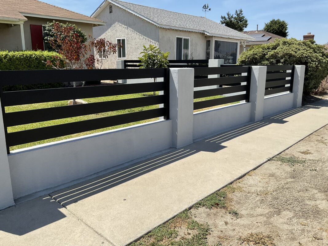 Modern black aluminum fence installed along a residential property line.