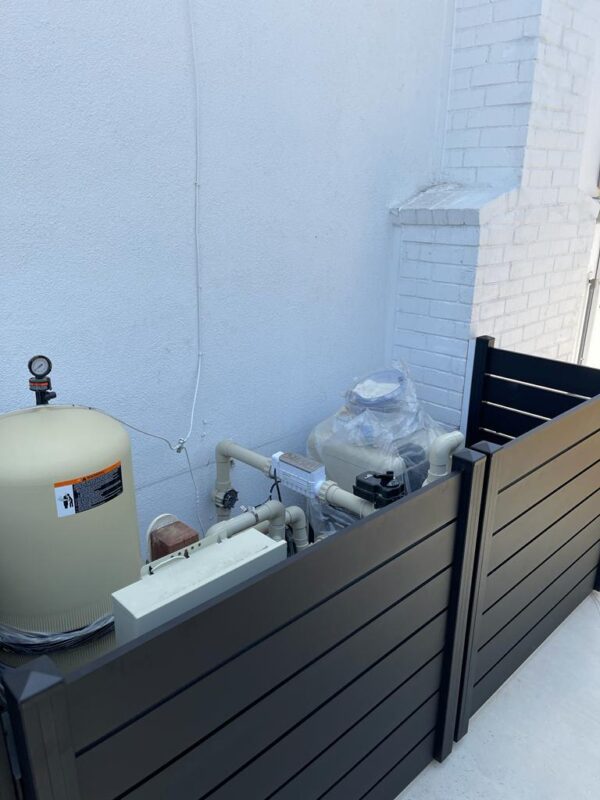 Black aluminum fence enclosing pool equipment, ensuring safety and aesthetics.