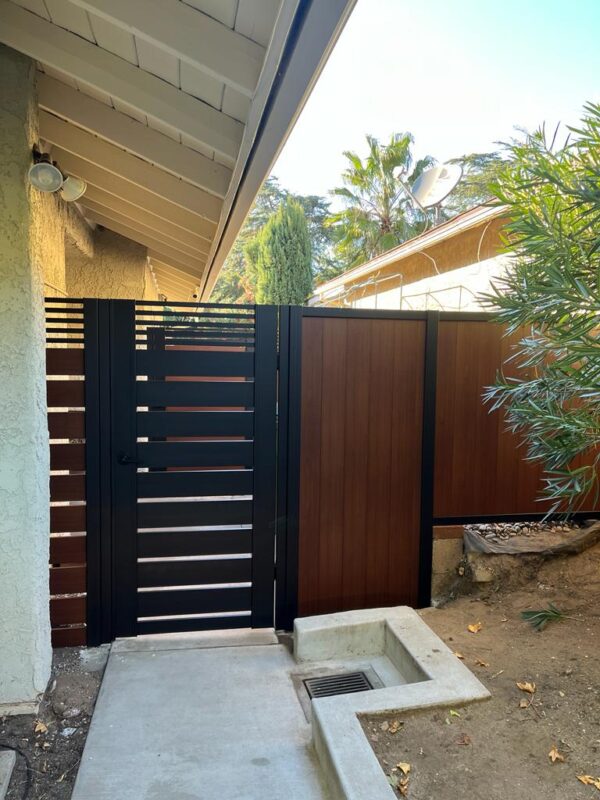 Modern black and wood pedestrian gate enhances privacy and style in a Sylmar home.