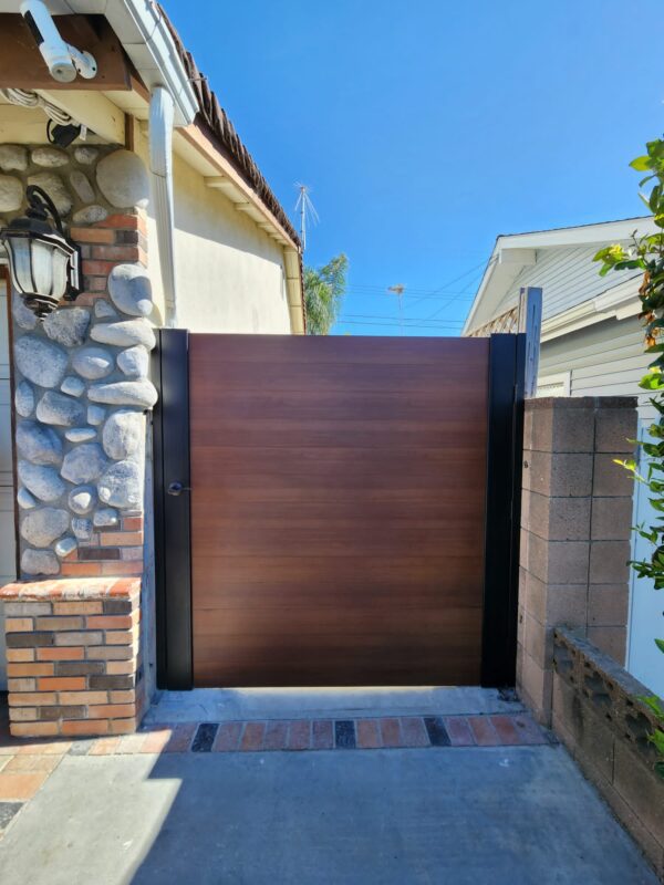 A modern gate with a wood-like finish installed in a residential area.