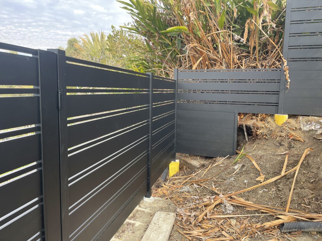 Black aluminum fence installation in Laguna Beach with modern design and landscaping.