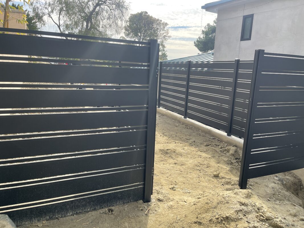 Close-up of modern black aluminum fencing installation on a construction site.