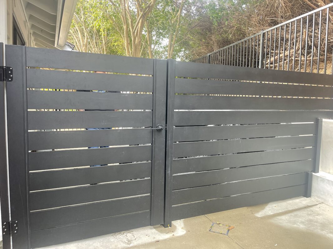 Modern black aluminum gate and fence panels in a residential installation.