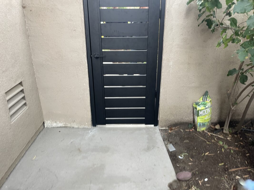 New black powder-coated aluminum gate installed next to a garden area.