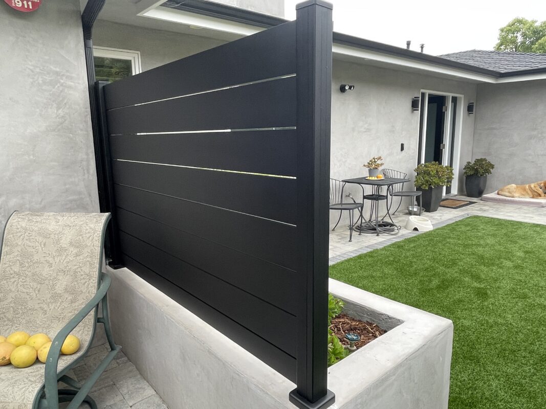 Modern black fence with horizontal slats, enhancing a coastal patio's privacy and style.