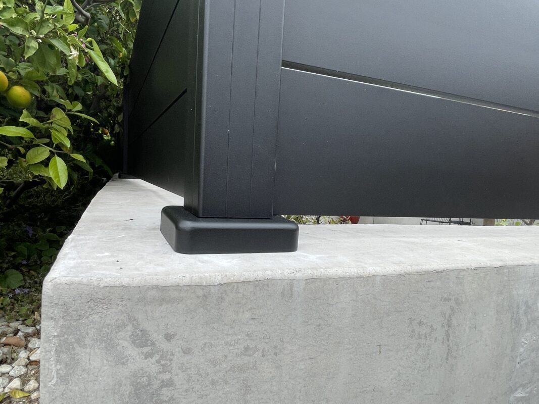 Close-up of a modern black LA wall topper installed on a concrete base.