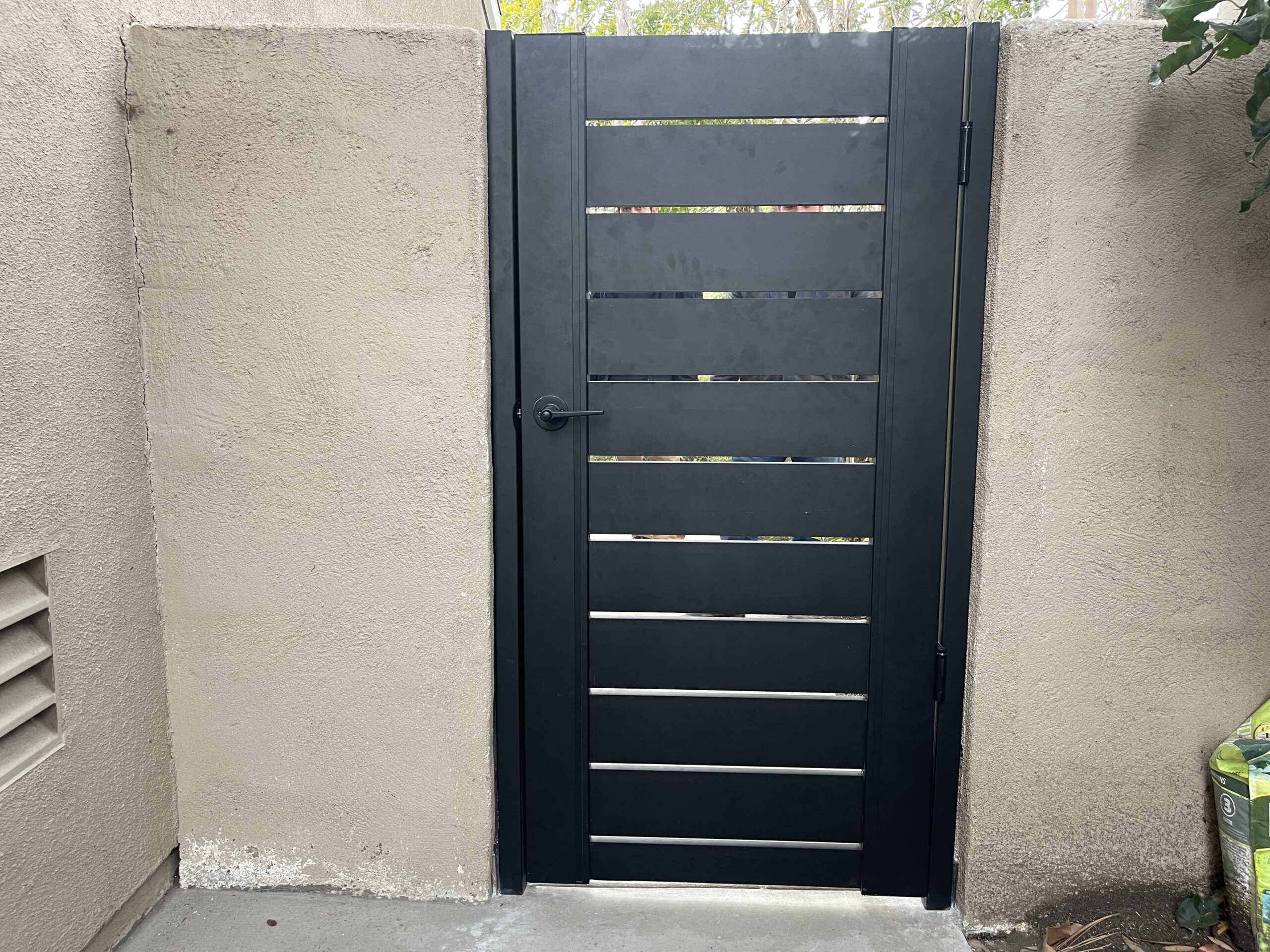 Modern aluminum gate installed against a smooth beige wall, enhancing security.