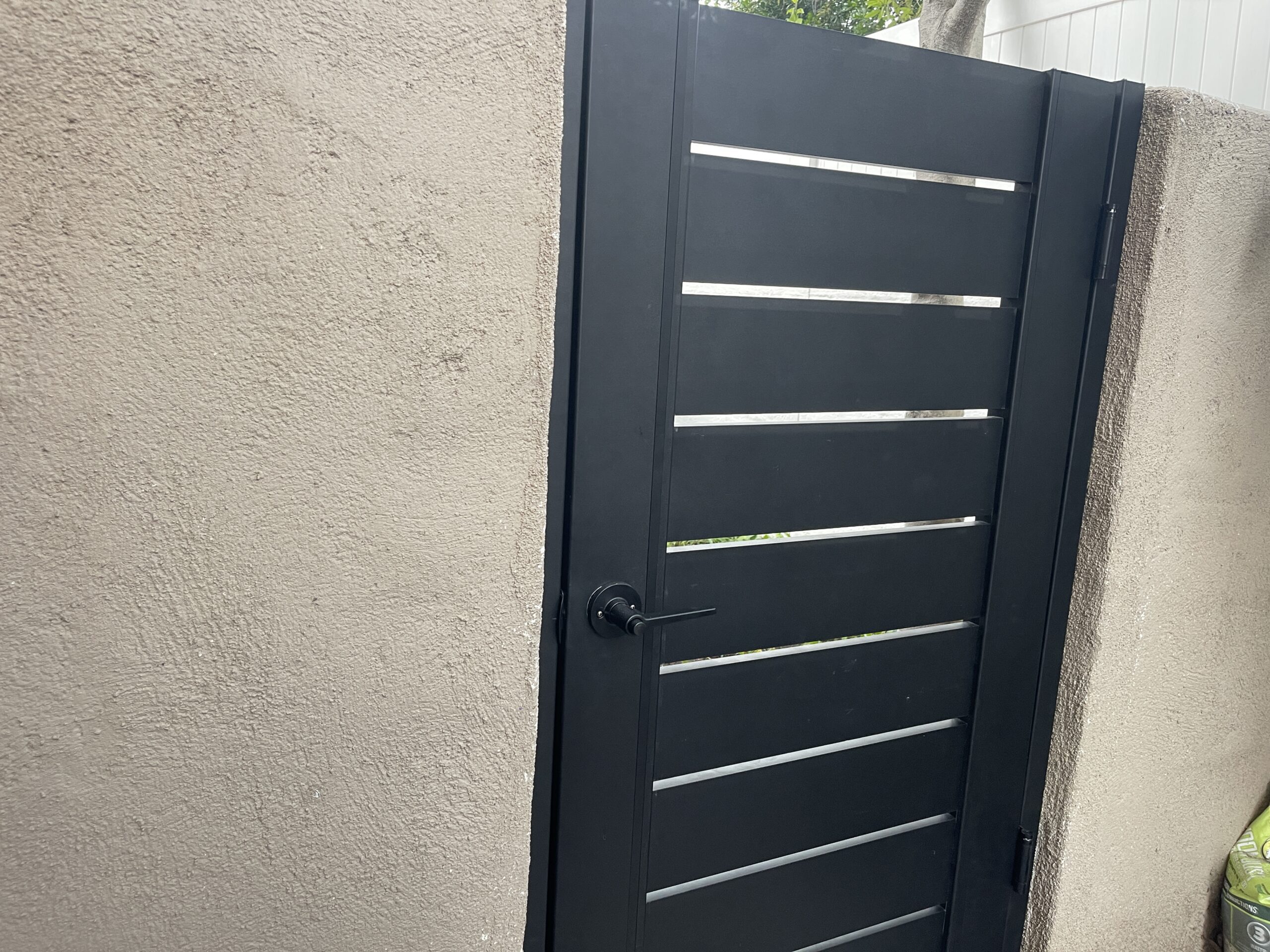 A modern black aluminum gate installed in a residential setting.