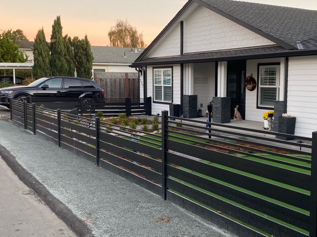 Black aluminum fence and gate enhance a modern home in Aptos with coastal landscaping.