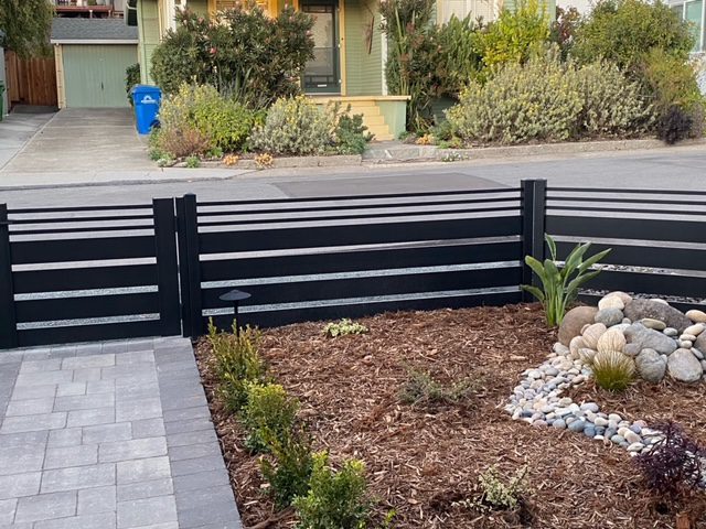 New black aluminum fence with gate enhances yard aesthetics and privacy.