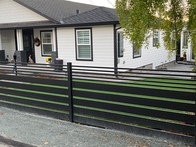 Modern black aluminum fence enhances a coastal home with stylish curb appeal.