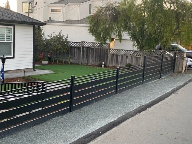 Sleek black aluminum fence installed around a yard with artificial turf in a residential area.