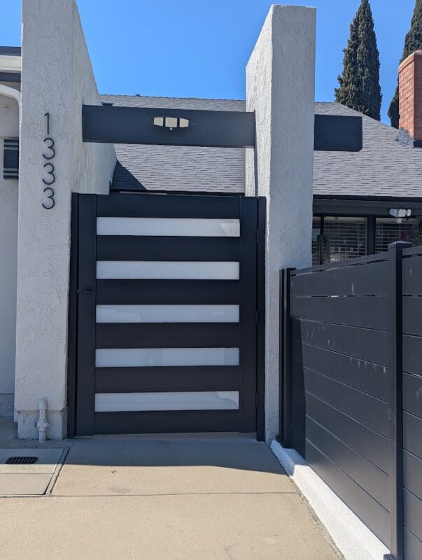 Modern black aluminum gate and fence installation at a residential property.