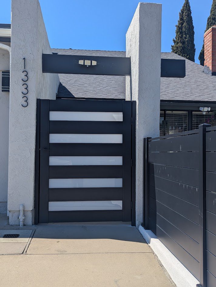 Modern black aluminum gate and fence installation at a residential property.