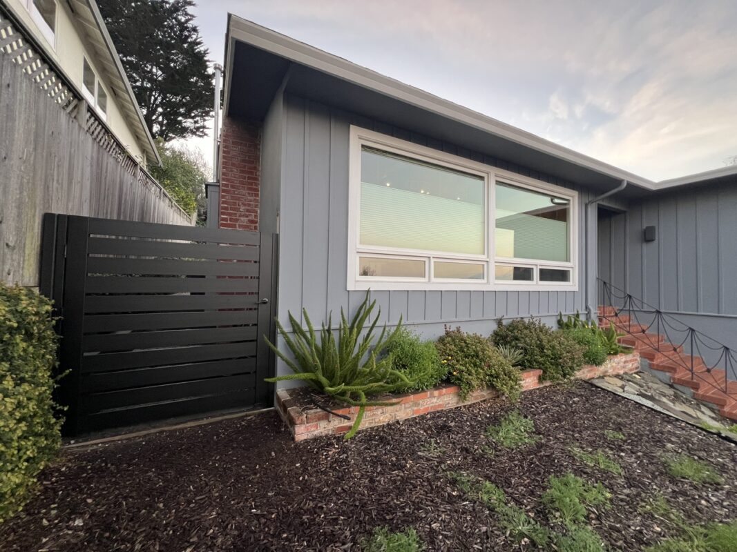 A sleek black LA style gate enhances a home's entryway, adding security and style.
