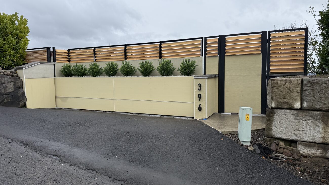 Modern driveway gate installation with wood and metal, enhancing privacy and aesthetics.