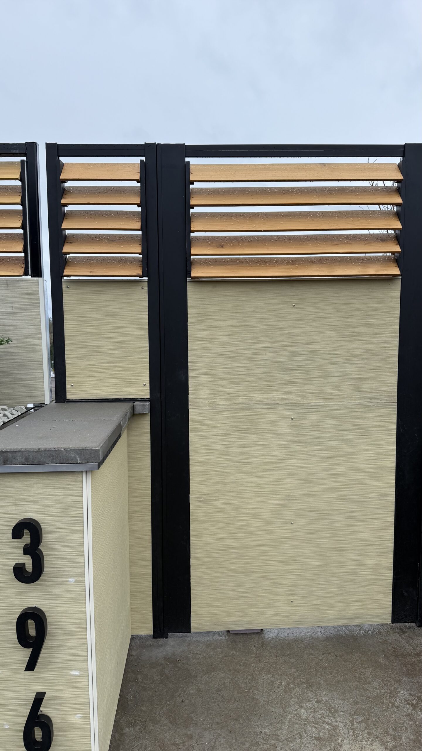 Modern fence installation showing a sleek driveway gate with wood accents.