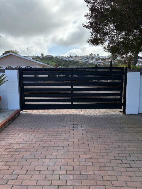 Black aluminum driveway gate installed in Van Nuys, CA, featuring a modern design.
