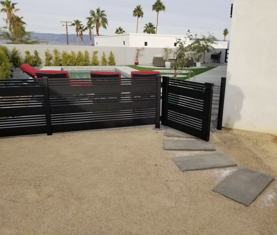 Matte black aluminum pedestrian gate with horizontal slats in a desert setting.