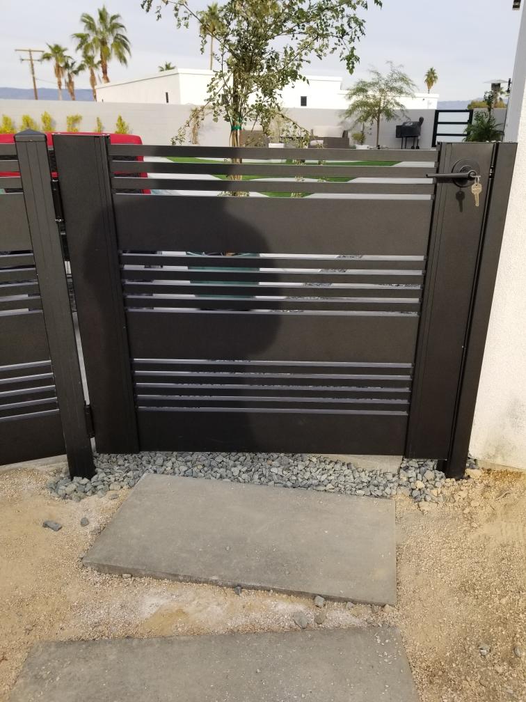 Matte black aluminum gate with horizontal slats, installed in a modern landscape.