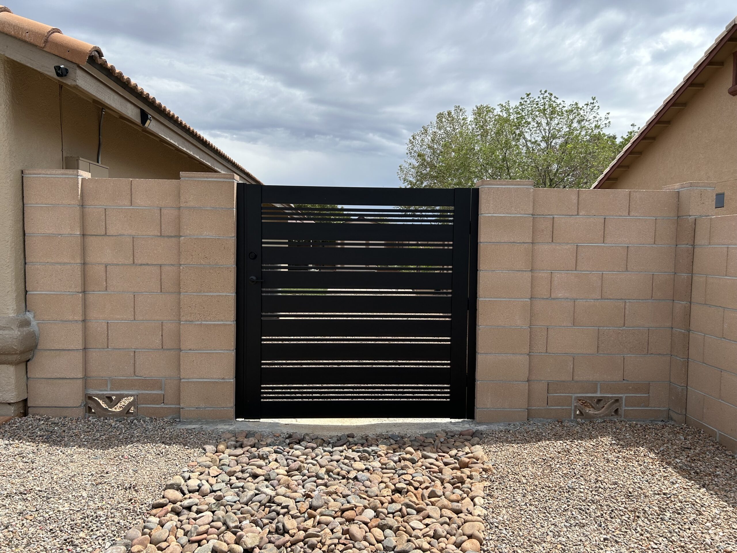Modern matte black aluminum gate installed within a stone wall in Sierra Vista, AZ.