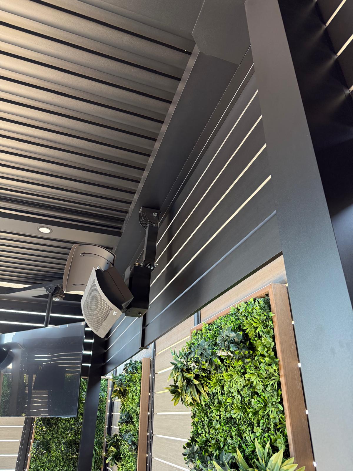 Modern matte-black aluminum fence with green plants, showcasing privacy and style.